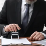 Hombre de traje sellando documentos, parte de la guía para tercerizar trámites notariales y de oficina en Bogotá.